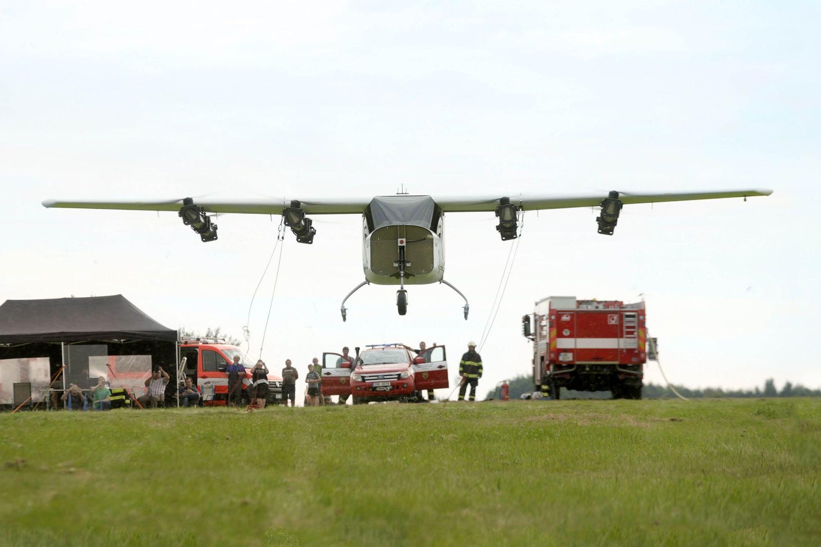 TD 1.0, the 11-meter demonstrator, in full-scale hover over the test field, crew and emergency vehicles standing by