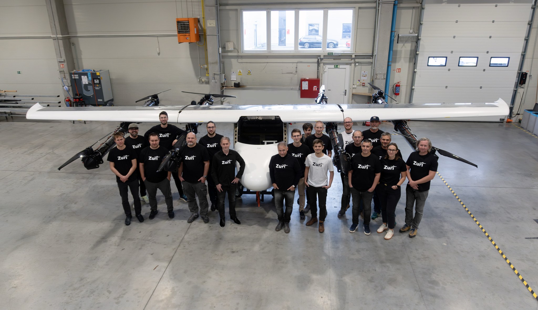 The Zuri team standing with aircraft in the Prague workshop hangar