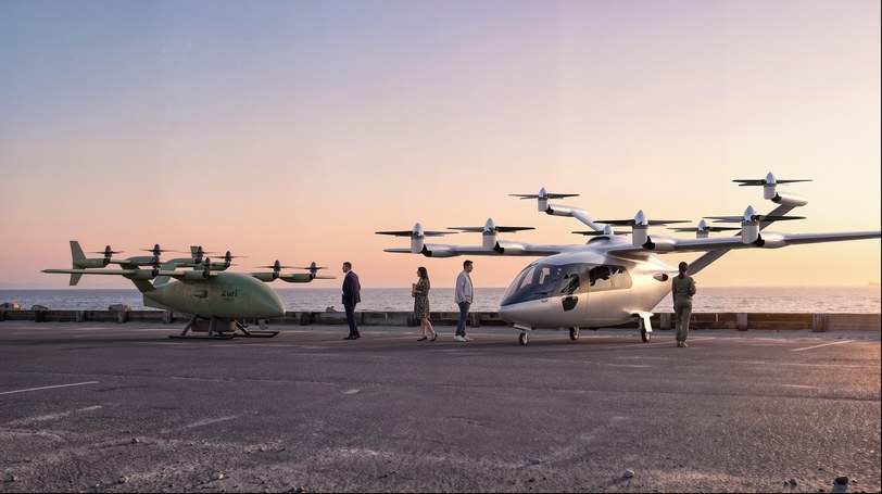 Render of the olive uncrewed cargo aircraft and the white six-seat passenger aircraft on a coastal quay, people walking towards the six-seater