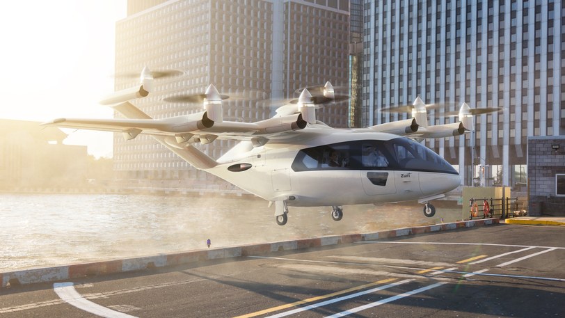 Render of the six-seat aircraft settling onto a street-level pad between city towers, sun low behind it