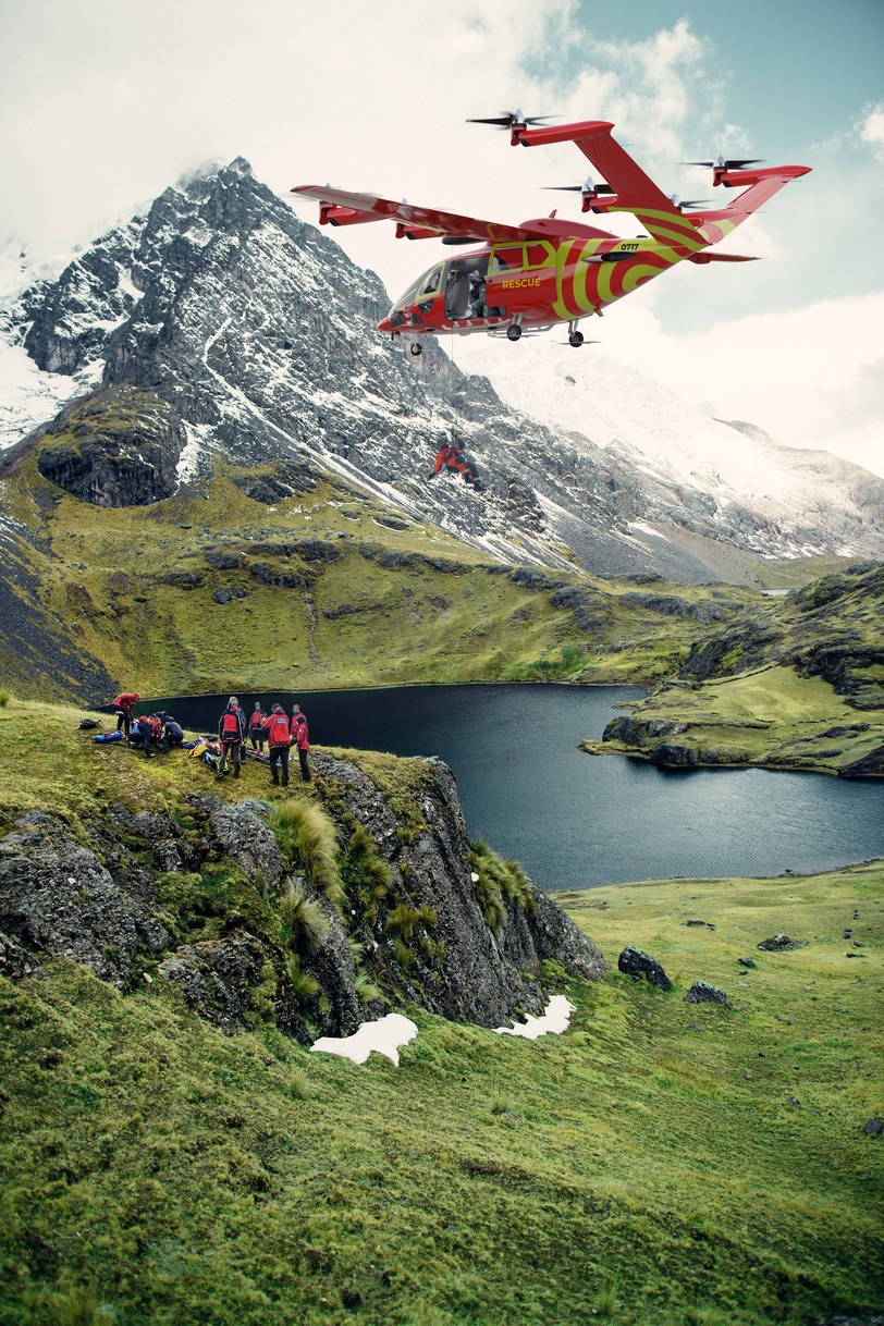 Render of the aircraft in red and yellow rescue livery flying past a snow-covered peak, a rescue team gathered on the green clifftop below