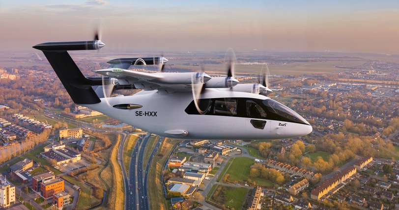 Render of the six-seat aircraft in cruise above a town at dusk, roads and rooftops below