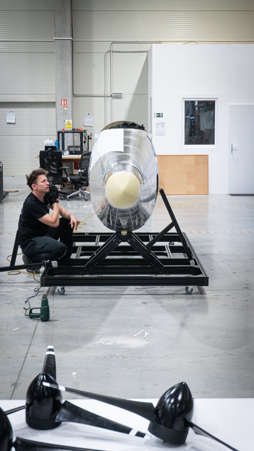 The TD 2.0 fuselage on its steel cradle in the hall, propeller blades on the floor beside it