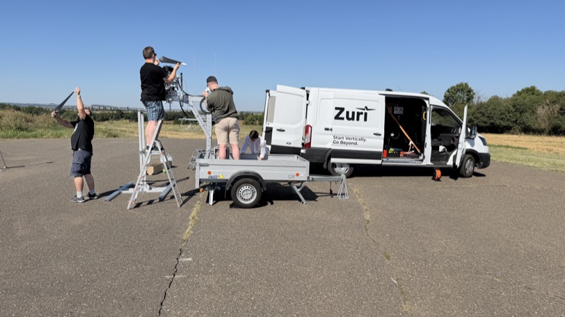 Three Zuri engineers running the TD 2.0 propeller test on the airfield, the Zuri van behind them