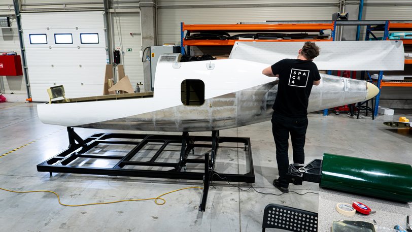 A Zuri technician wrapping the fuselage of the TD 2.0 display aircraft, which sits on its steel cradle in the Prague hall
