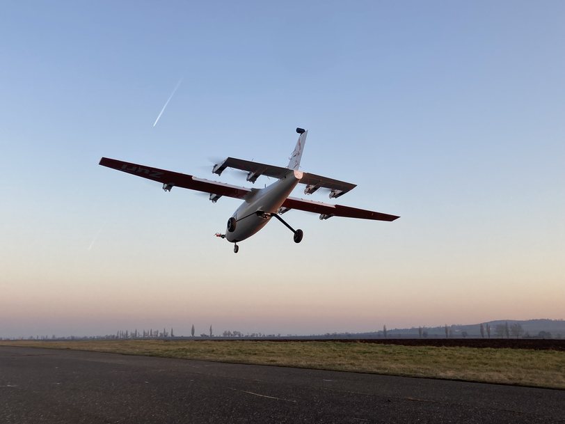 The Zuri V1NG subscale demonstrator flying low along a runway at dusk