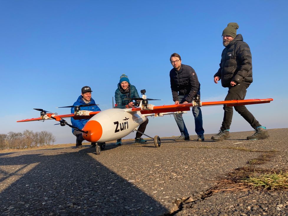 Zuri team members with scale VTOL prototype on runway, representing February 2025 expansion with new leadership and engineering hires to drive next-phase growth
