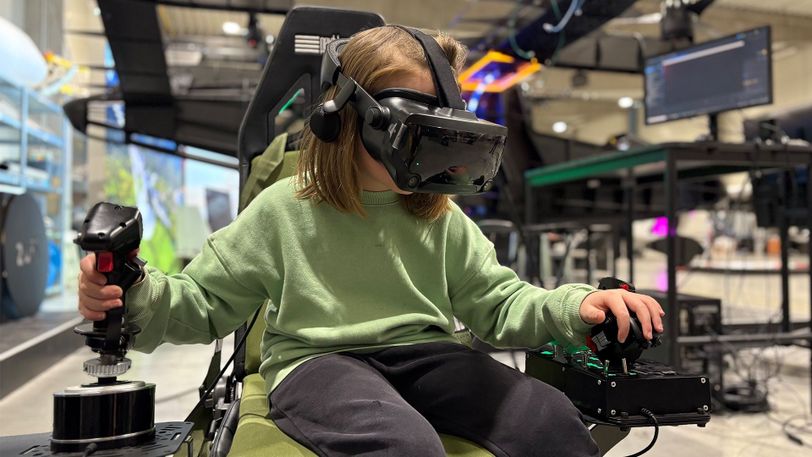 Child using VR flight simulator during Zuri Family Day, demonstrating interactive flight controls.