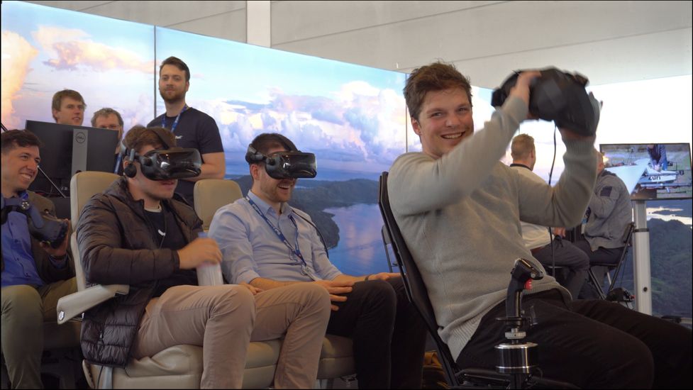 Visitors experiencing Zuri Hybrid VTOL virtual reality flight simulator at Aero Friedrichshafen 2023, showcasing immersive pilot and passenger experience.